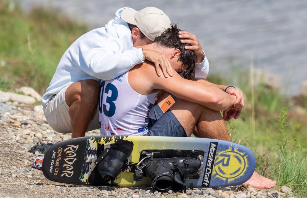 Joel Poland of Great Britain is consoled by friend Edoardo Marenzi of Italy after Poland fell early in his trick run during the 2025 IWWF World Waterski Championships at Parco Nautico del Sesia in Novara, Italy.